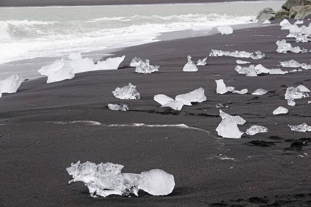 Blocks of ice laying on black volcanic sand - Diamond Beach, Jokulsarlon, Iceland - Foto, Imagem