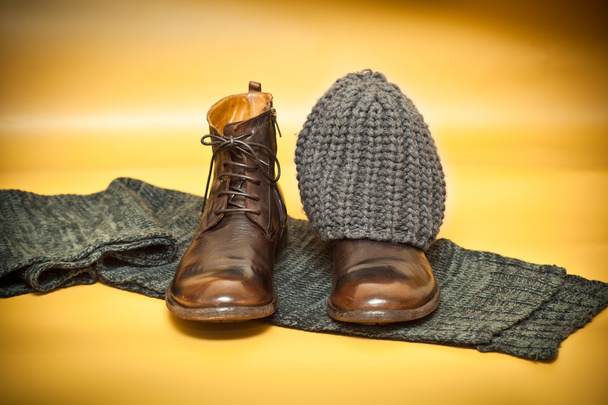 Brown fashion leather shoes, knitted scarf and cap on an abstract background yellow. still life of clothes - Photo, Image