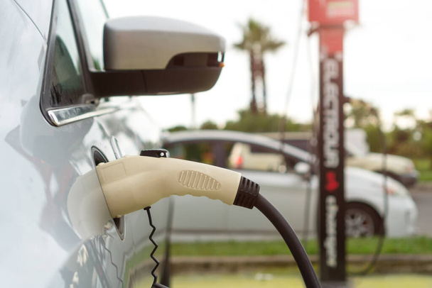 Close-up of charging a car in the parking lot. White electric car is charging. - 写真・画像
