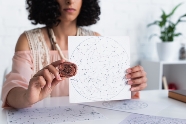 частковий вигляд оракула, що тримає глиняну руну і карту сузір'їв
  - Фото, зображення