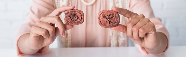 cropped view of fortune teller holding clay runes while predicting at home, banner - Foto, imagen