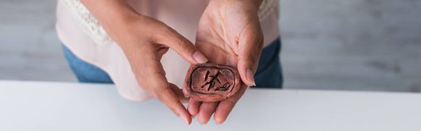 cropped view of clay rune in hands of cropped fortune teller, banner - Zdjęcie, obraz