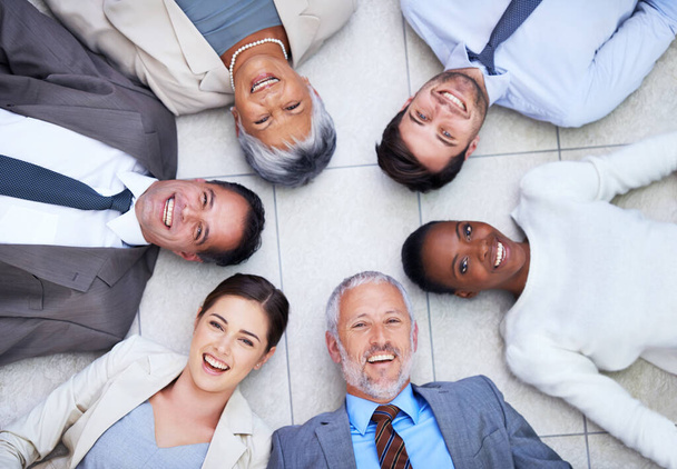 Its important to have good business relationships. High angle portrait of a group of diverse businesspeople lying on the floor in a circle - Photo, Image