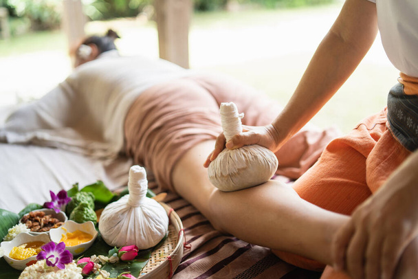 Massage spa relaxing treatment of office syndrome traditional thai massage style. Asian female massage traditional compress for hot massage leg pain, arm pain and stress for woman tired from work. - Foto, afbeelding