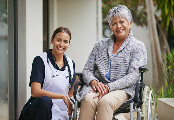 Her care and support makes the world of difference. Portrait of a senior woman in a wheelchair being for for by a nurse at a retirement home - Foto, Imagem