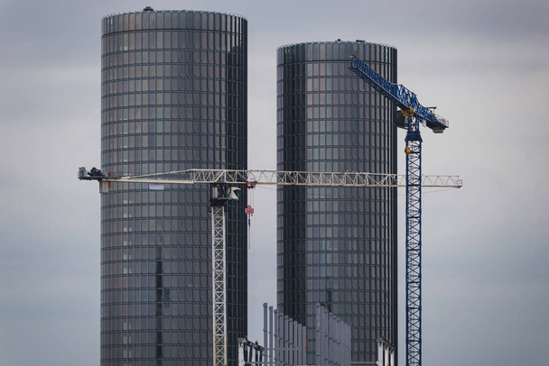 Two large construction cranes on the background of skyscrapers. Construction concept, construction of high-rise buildings, construction of office buildings and apartments. - Foto, Imagem