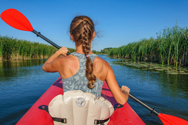 A sporty girl in a red kayak paddles along the Zdvizh River. Ukraine - Foto, afbeelding