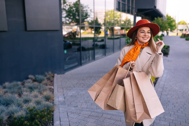 Image of happy woman with paper bags walking down the street - Foto, Imagen