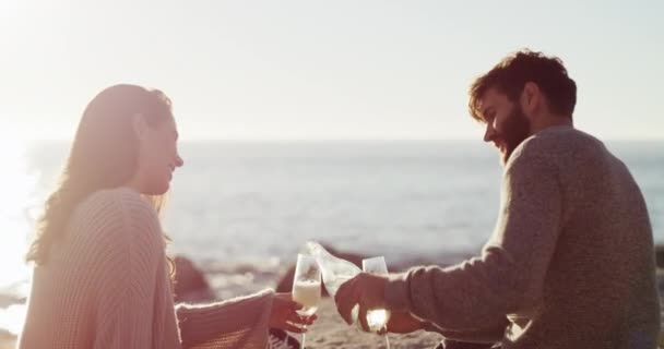Couple with champagne glass on picnic at beach, celebration of love on holiday date and giving cheers at sea in summer. Travel, smile and wine man and woman with alcohol for happiness on vacation. - Materiał filmowy, wideo