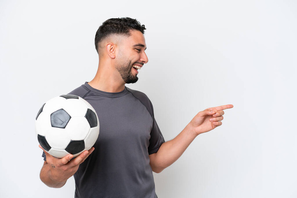 アラブの若いサッカー選手の男は、側に指を指して、製品を提示白い背景に隔離 - 写真・画像
