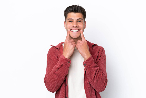 Young caucasian man isolated on white background smiling with a happy and pleasant expression - Φωτογραφία, εικόνα