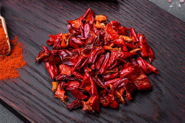 Pieces of dried paprika, preparation of powder spice for various dishes, against a dark concrete background - Foto, Imagem