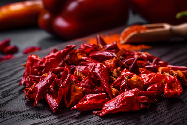 Pieces of dried paprika, preparation of powder spice for various dishes, against a dark concrete background - Fotografie, Obrázek