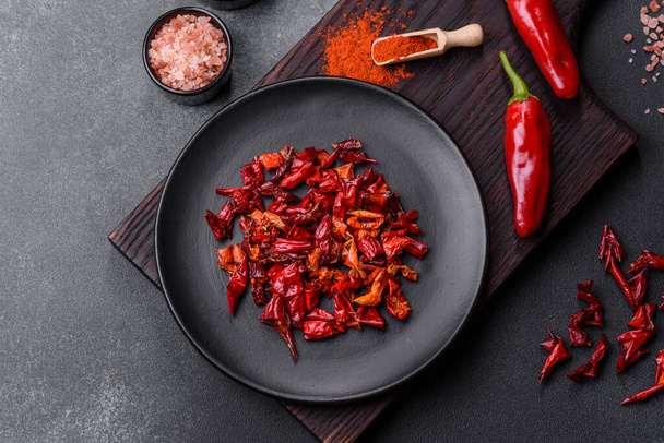 Pieces of dried paprika, preparation of powder spice for various dishes, against a dark concrete background - Foto, Imagen