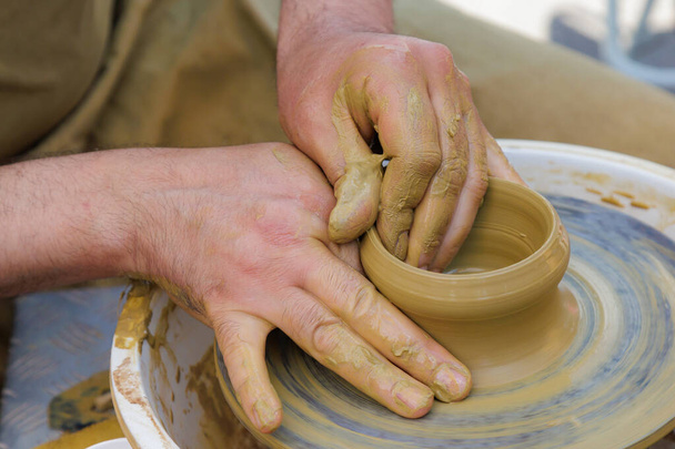 Potter in the process of working on a potters wheel. Close-up hands. Background with copy space for text - Fotografie, Obrázek