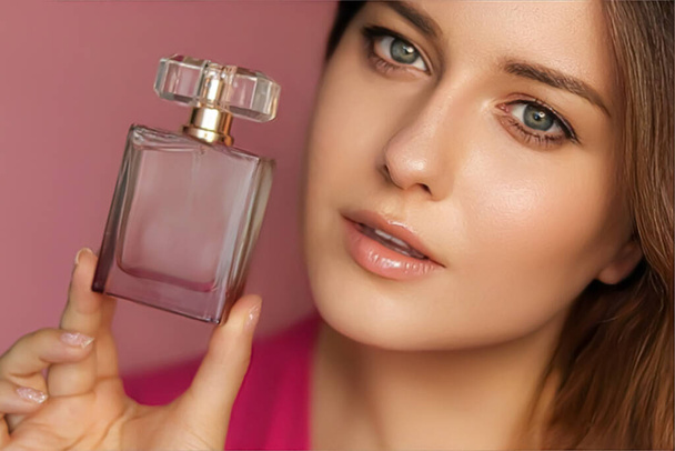 Perfume, producto de belleza y cosméticos modelo retrato facial sobre fondo rosa, hermosa mujer sosteniendo botella de fragancia con aroma femenino floral, moda y concepto de maquillaje - Foto, imagen
