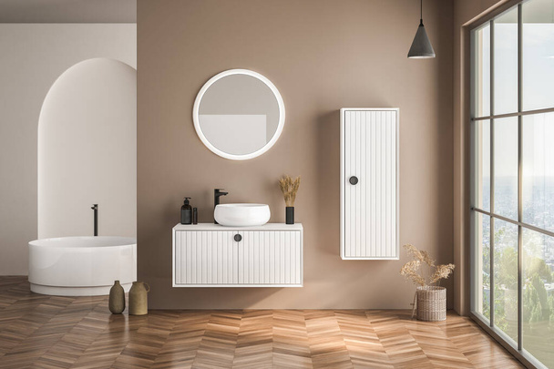Modern bathroom interior with beige walls, white basin with oval mirror, bathtub and parquet floor. Minimalist beige bathroom with modern furniture. 3D rendering - 写真・画像