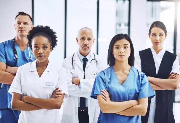 Тир потрібна медична команда. Обрізаний портрет групи медичних працівників, що стоять зі складеними руками в лікарні
 - Фото, зображення