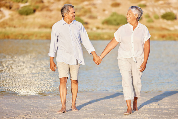Love, walking and senior couple on a beach lake together for calm, relax and romantic ocean, water or sea date. Elderly happy people, man and woman smile while living pension and retirement lifestyle. - Foto, imagen