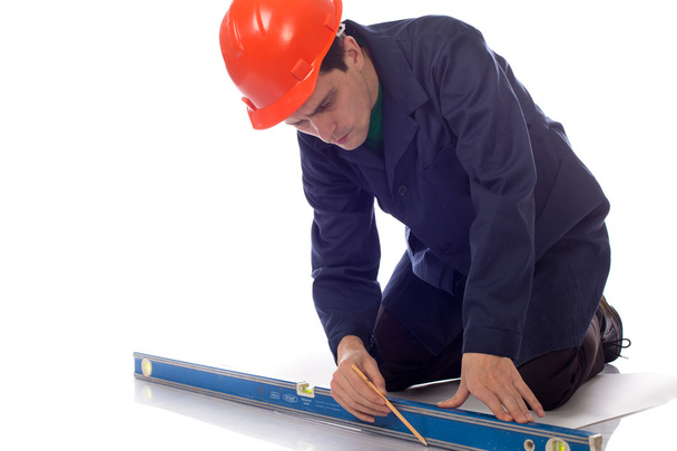 man in builder helmet and blue robe draws pencil on sheet - Φωτογραφία, εικόνα