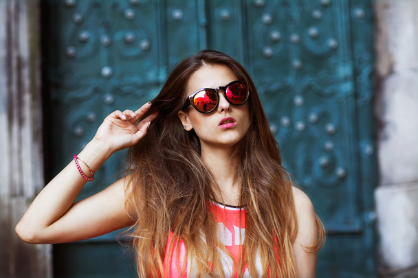 Fashion beautiful girl in sunglasses standing near the turquoise walls - Фото, изображение