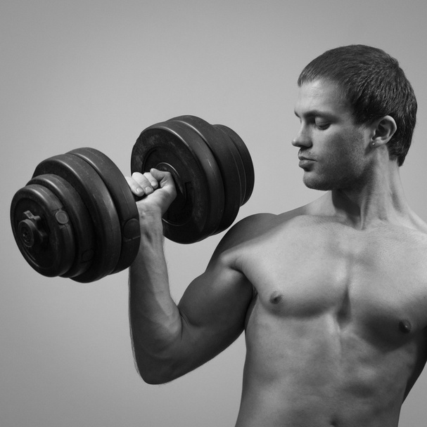 Handsome muscular male model with dumbbell. Black and white. - Foto, immagini