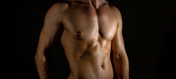 Unrecognizable muscular male body on black background. - Foto, afbeelding