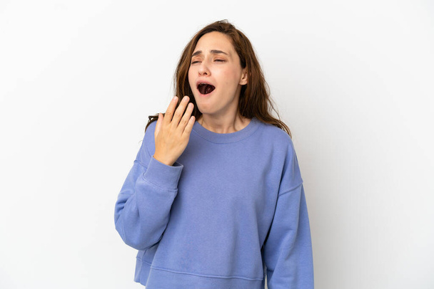 Молода біла жінка ізольована на білому тлі позіхання і покриває широкий відкритий рот рукою
 - Фото, зображення
