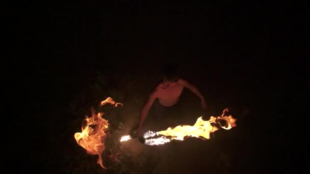 Képzett tűz táncos úgy néz ki, a kamera, dob a tűz személyzet felé kamera és fogás, végez tűz spinning, felülről lefelé lövés, lassú mozgás (60 fps) - Felvétel, videó