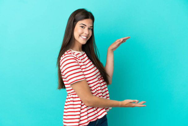 Young Brazilian woman isolated on blue background holding copyspace to insert an ad - Foto, immagini