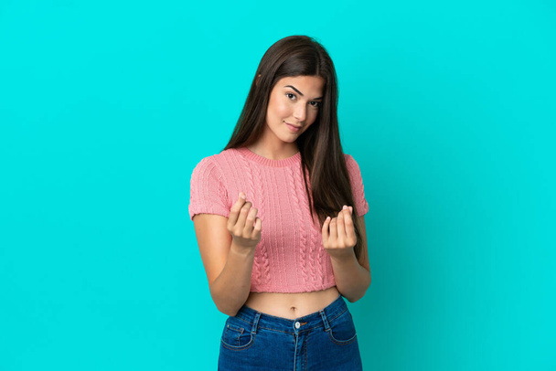 Young Brazilian woman isolated on blue background making money gesture but is ruined - Photo, Image