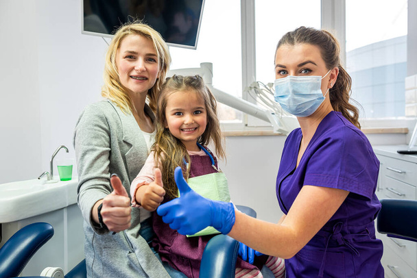 little girl's mother and dentist soothe little girl before dental treatment. The concept of approach to children in dentistry - Foto, afbeelding