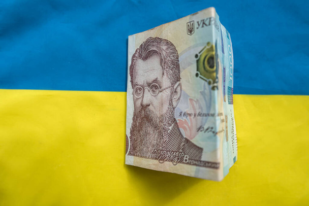 Ukrainian hryvnia lying on national blue yellow flag of Ukraine. Uah - Fotoğraf, Görsel