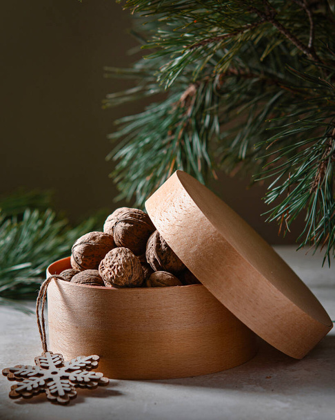 Round wooden basket with walnuts, New Year or Christmas gift under the tree, holiday celebration - Foto, imagen
