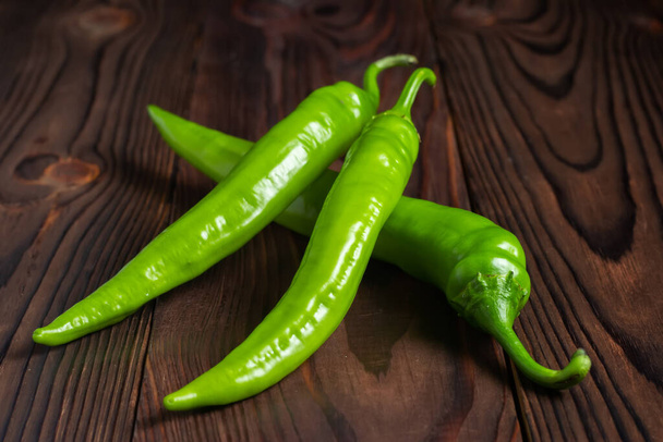 Group of green bitter peppers on wooden background. - 写真・画像