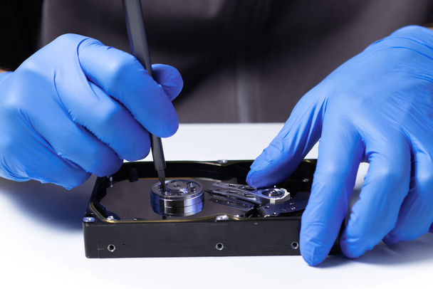 Repair Hard disk. Hands of master in gloves with screwdriver repair the computer hard drive. Data cleaning, HDD recovery - Photo, Image