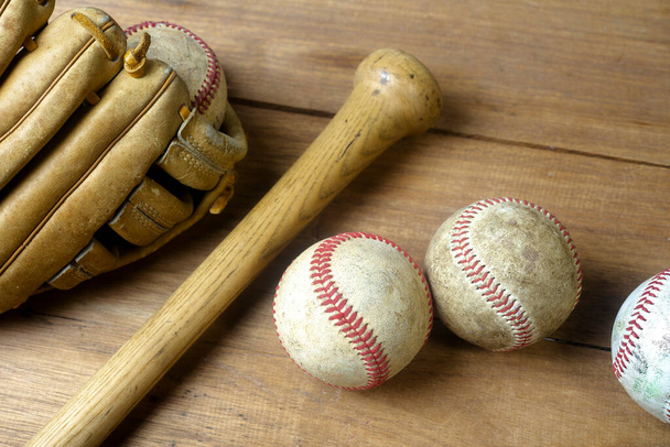 Close up old baseball, wooden baseball bat and baseball glove on a woodeb table. select focus. - Fotografie, Obrázek