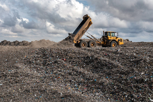 A dumper truck on a large waste management landfill site dumping rubbish in an environmental issue image - Fotó, kép