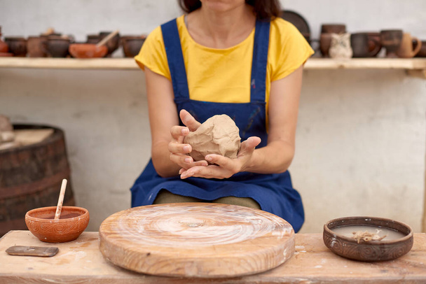 Поттер з мокрим глиняним горщиком в руках. гончарне хобі жінка руки скульптури в глині
 - Фото, зображення