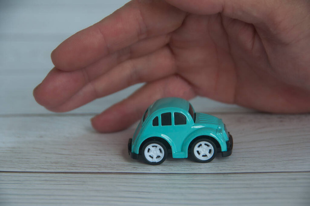 Hand covering toy car - Insurance and security concept. - Foto, immagini
