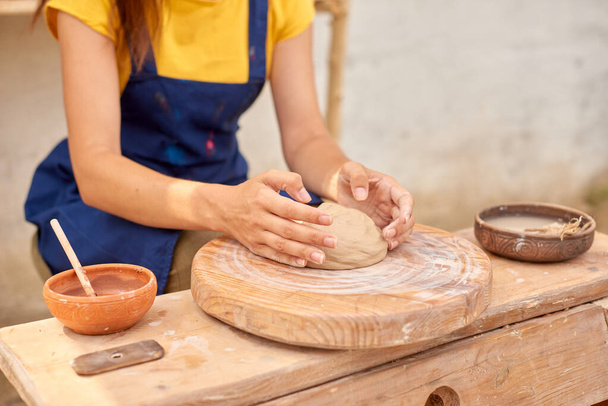 woman hands with piece of clay on wooden potter's wheel - Foto, afbeelding