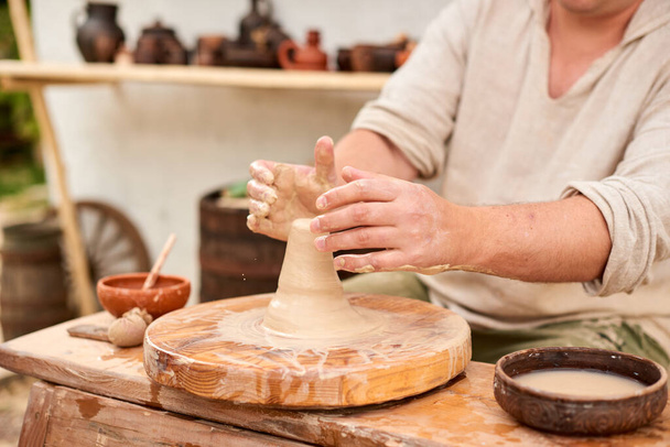 male master in light linen shirt pottery crafter man hands sculpt in clay - Foto, Imagen