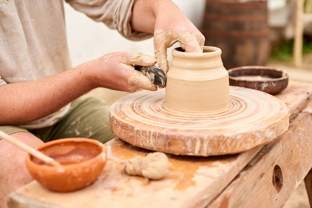 male craftsman sculpts jug or vase from clay - Foto, Imagen