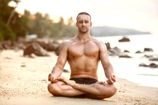 Man practice yoga on the beach at sunset - Foto, Bild