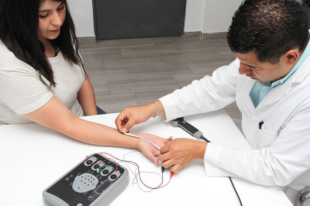 Latin doctor specialist neurologist performs a study of evoked potentials, diagnostic techniques with sensory stimuli and the recording of stimulated brain responses to a female patient. - Zdjęcie, obraz