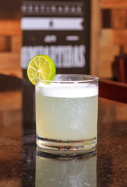 Nízký úhel zblízka ledové studené moderní gurmánské řemeslné koktejl gin a tonic soda zdobené citrónem plátky a rozmarýnem posypané bar pozadí - Imagen - Fotografie, Obrázek