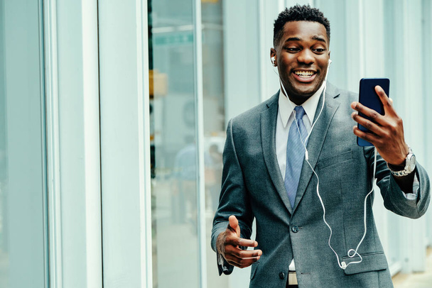 Positive young businessman using smartphone outside wearing suit and tie - Foto, Imagem