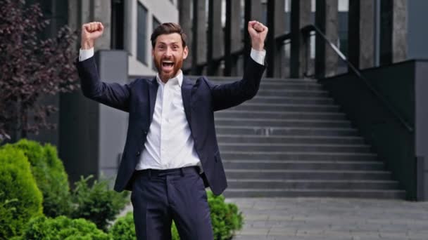 Excited happy businessman standing outdoors rejoicing in victory young male manager entrepreneur celebrating business success promotion professional achievement getting promoted making yes gesture - Πλάνα, βίντεο
