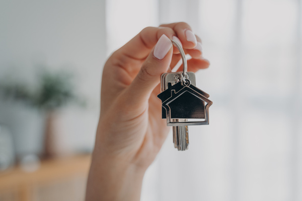 Key to new house. Close-up of female hand hold bunch of keys. Woman real estate agent realtor makes offer, showing key from new home apartment. Purchase of housing, copy space. - 写真・画像