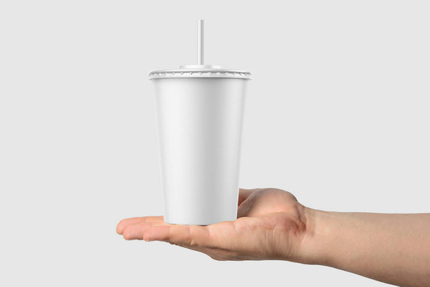 Paper soda cup in a hand with straw mockup template, isolated on light grey background. High resolution. - Foto, immagini